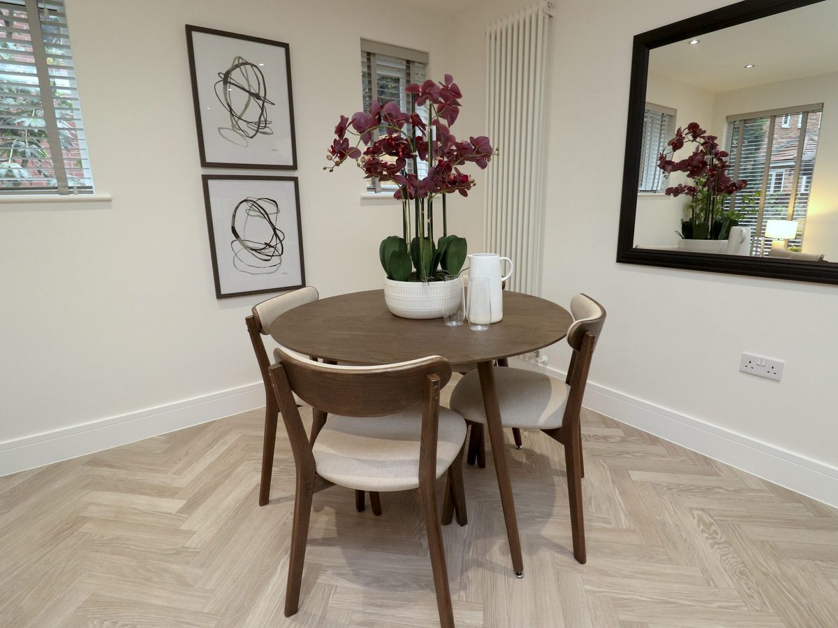 Round walnut dining table set with orchids, framed prints on the wall behind