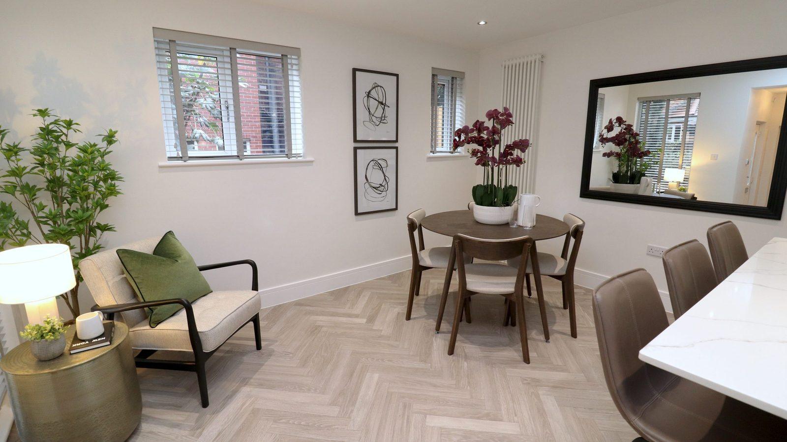 Staged dining room at Yew Tree Cottage: round walnut table, framed prints, orchids and a large mirror