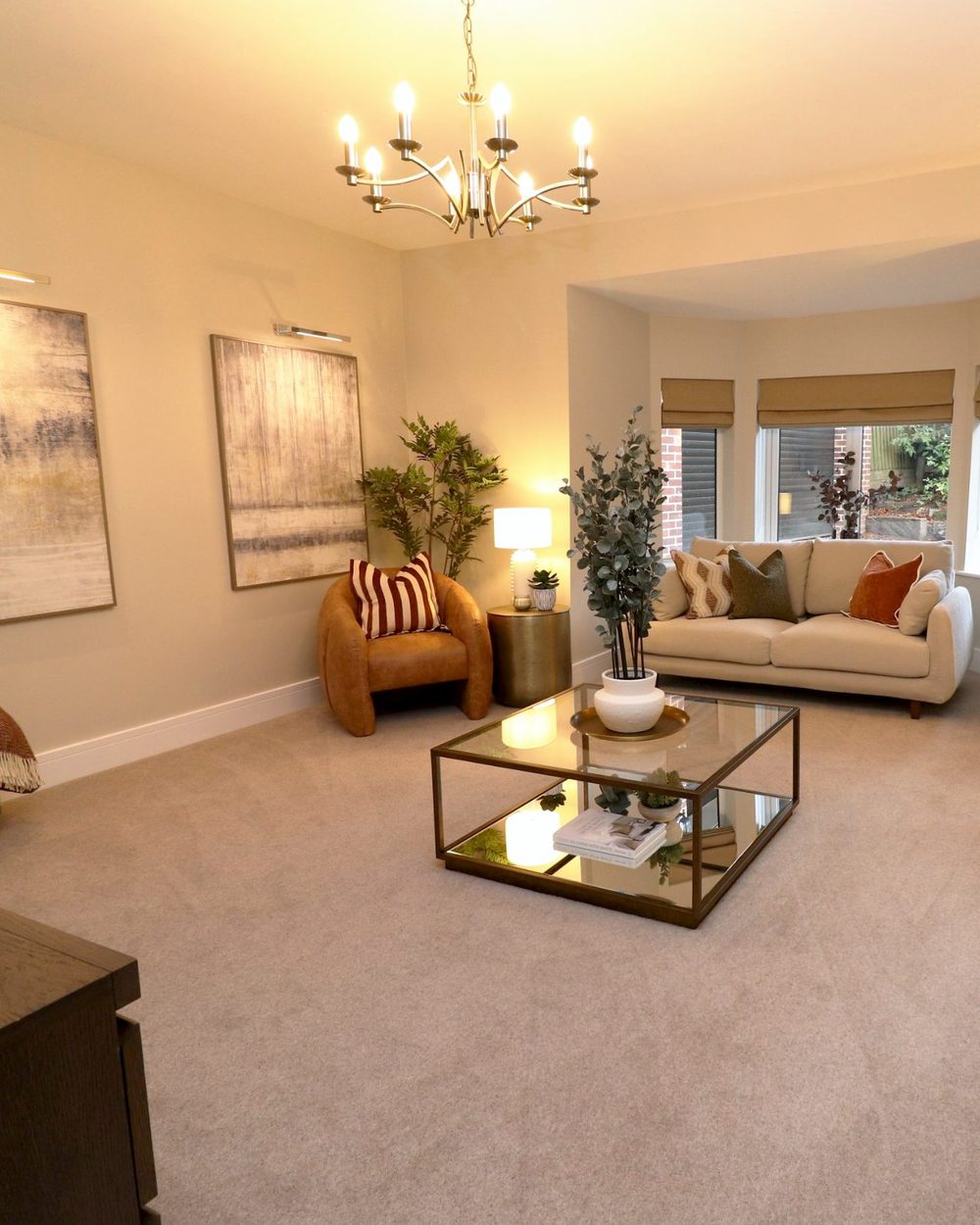 Brass chandelier and picture lights over two canvases in a staged living room