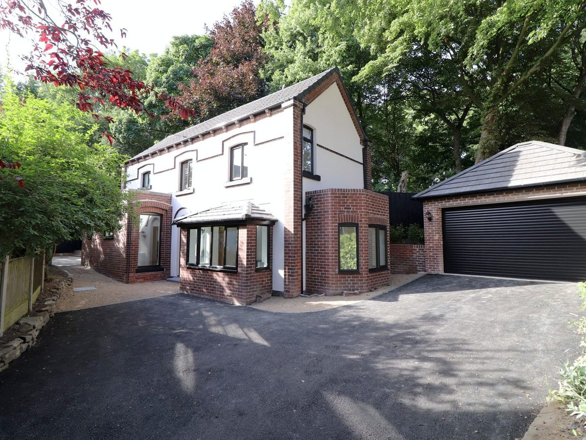 Yew Tree Cottage from the drive: white rendered house with red brick detailing and a double garage
