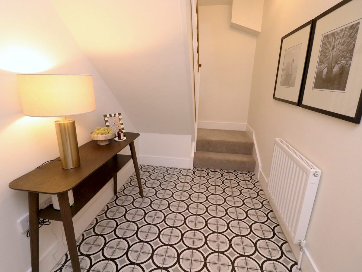 Hallway at Yew Tree Cottage: walnut console with a lamp, patterned tiles and the stairs