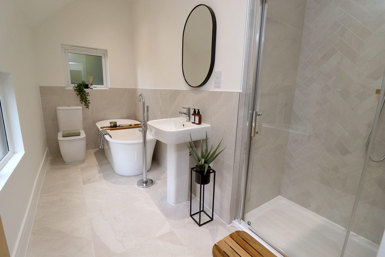 Bathroom after: oval mirror over the basin, plant stand, towels, wooden stool in the shower