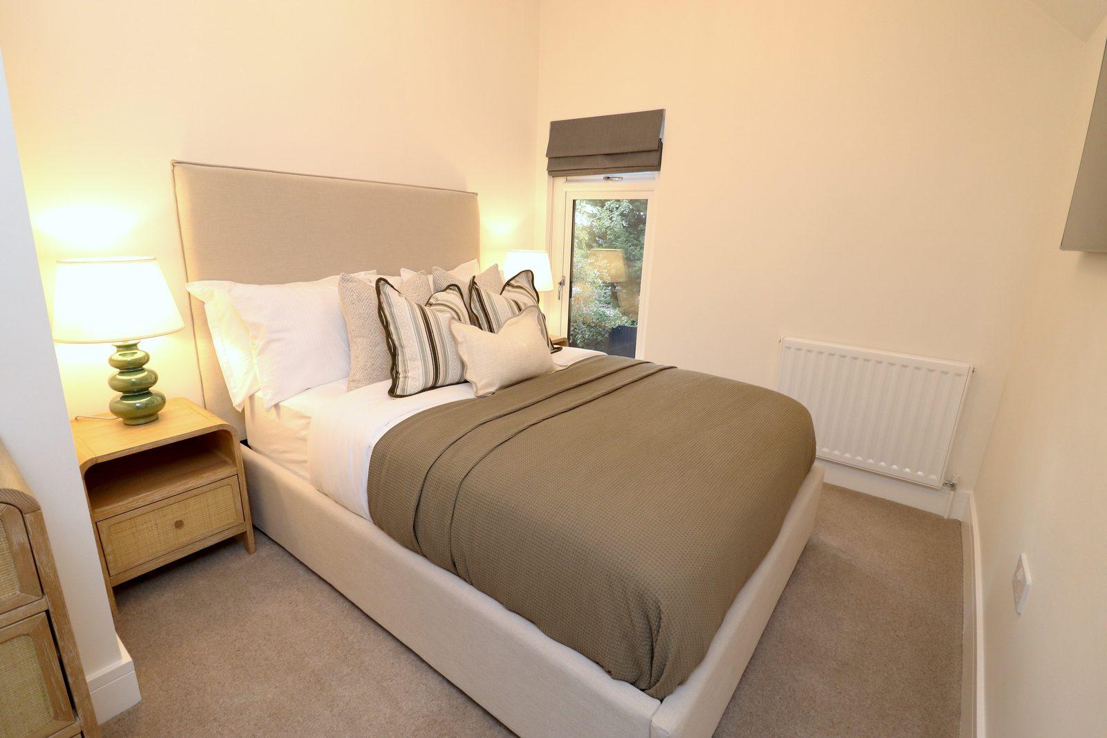 Second bedroom after: double bed with taupe throw, bedside lamp, large abstract canvas