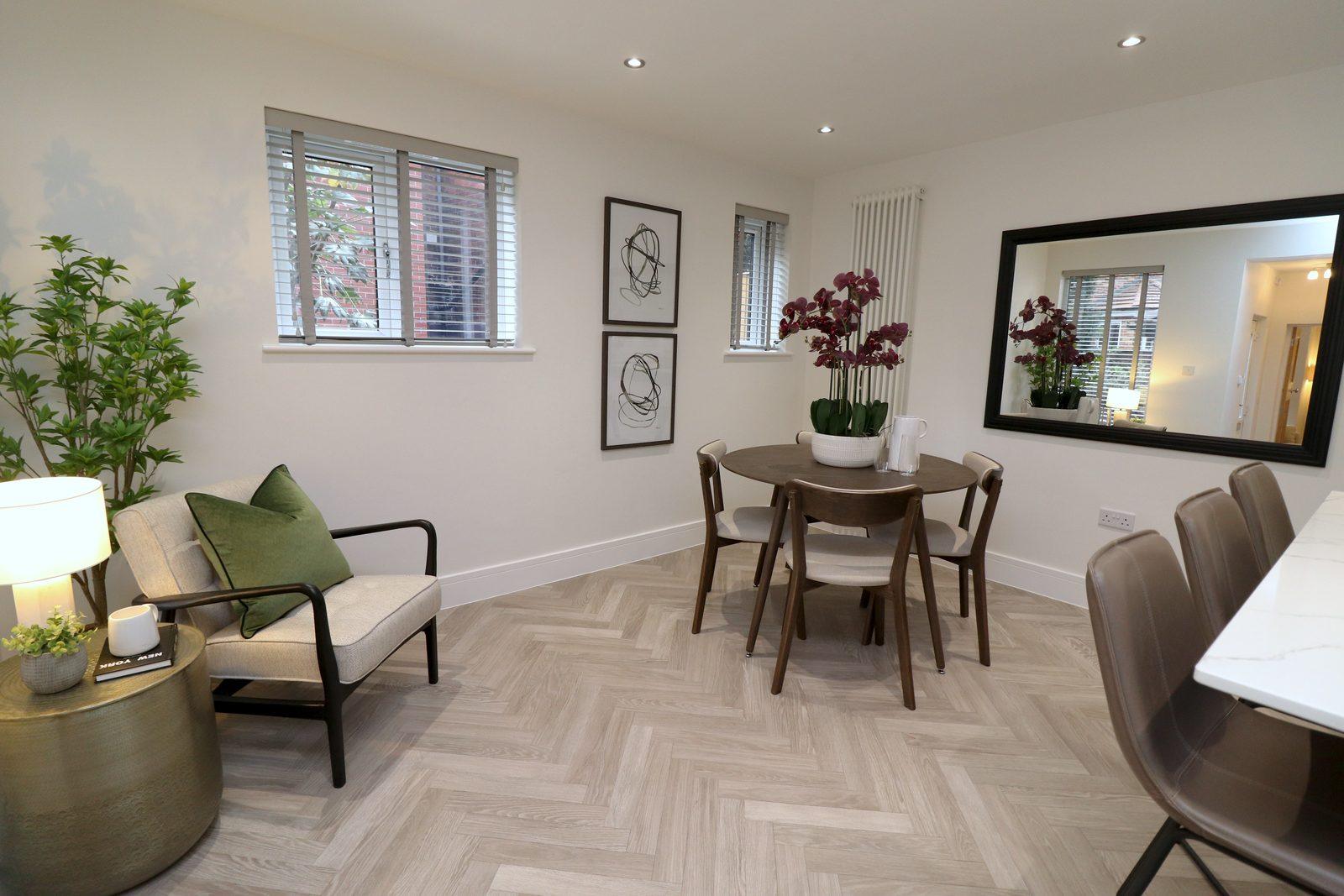 Dining area after: round dark wood table, four chairs, large mirror and two framed prints