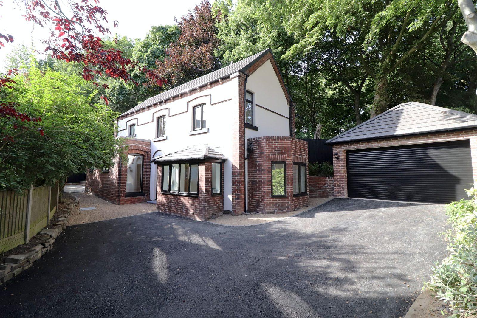 Yew Tree Cottage from the drive: white rendered house with red brick detailing, a bay window, and a detached double garage among mature trees