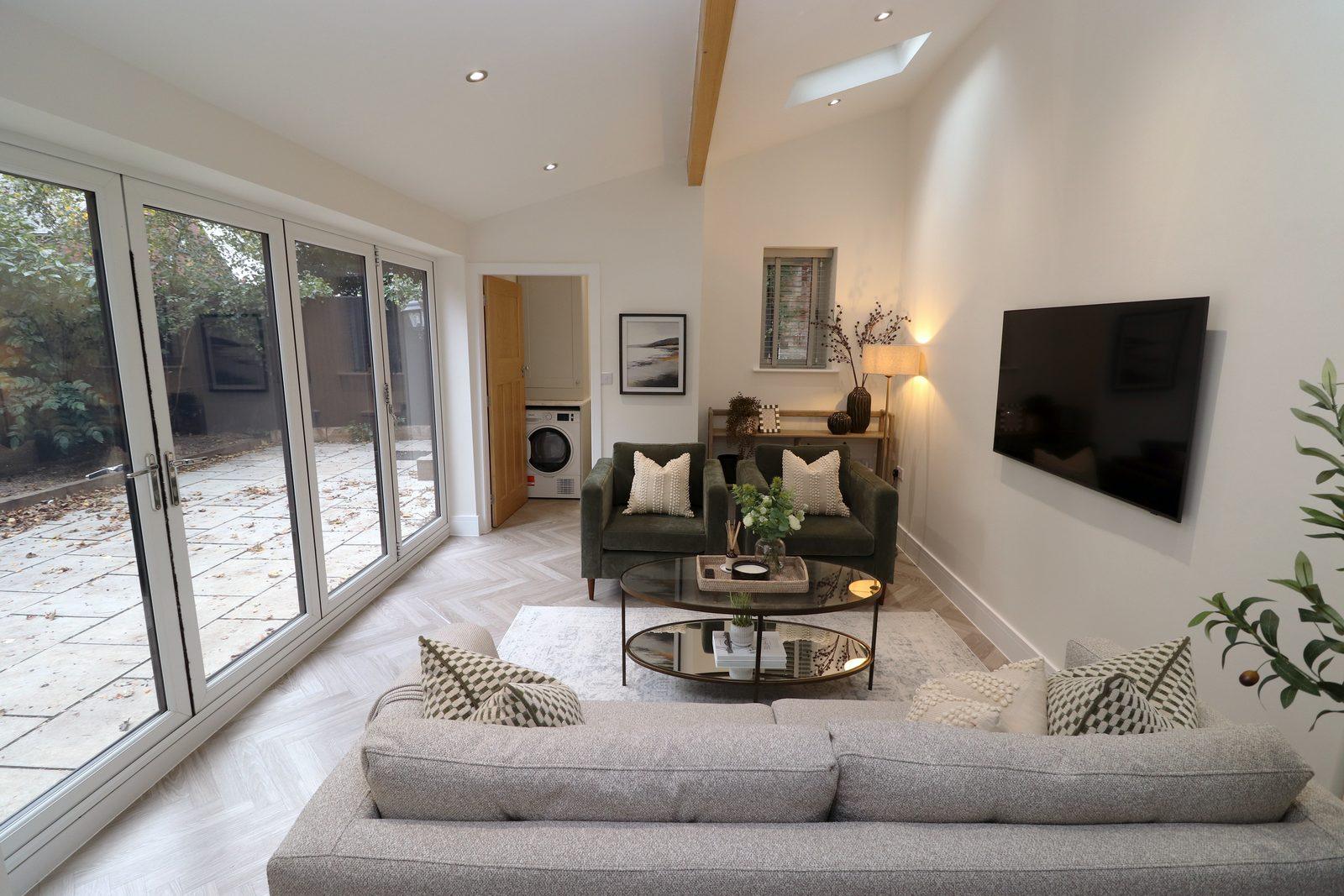 Family room after: grey sofa, two olive velvet armchairs, round coffee table, olive tree