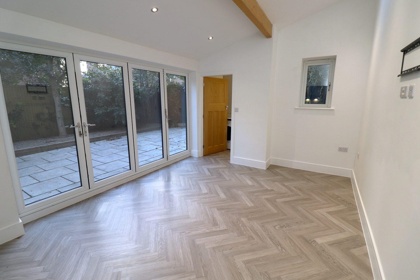 Family room before: empty room with bifold doors and herringbone floor