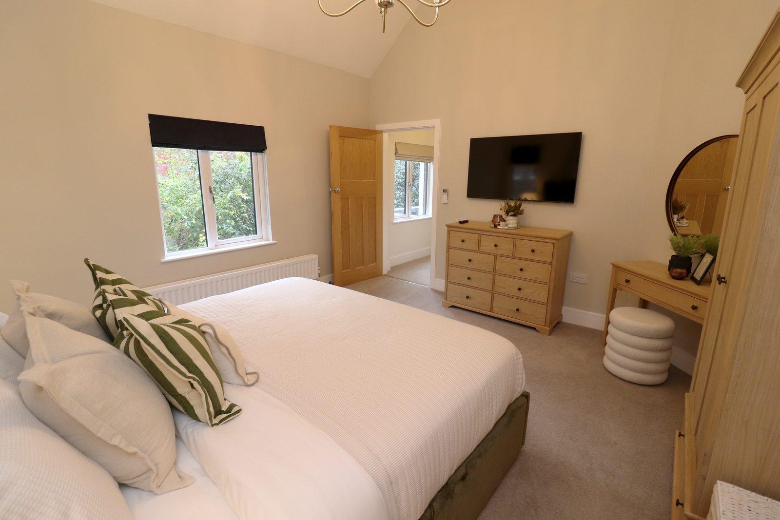 The bed from the side, chest and dressing table beyond