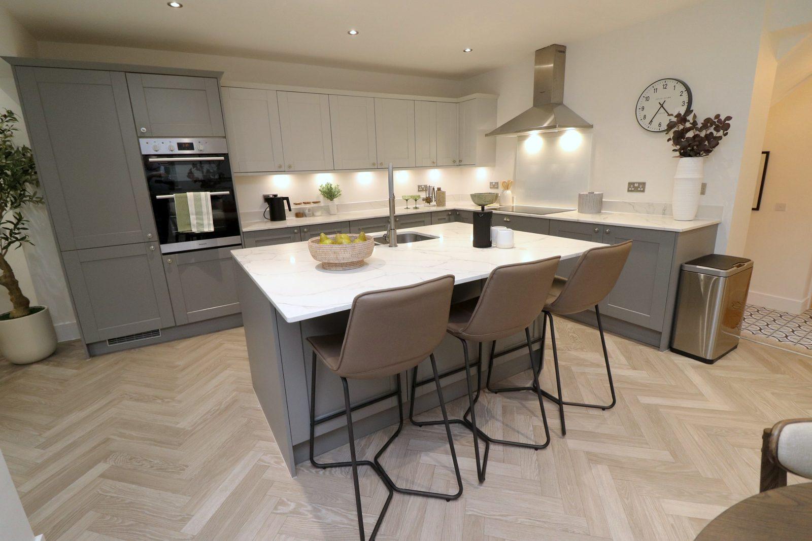 Kitchen island with bar stools, a bowl of pears, the hood and clock