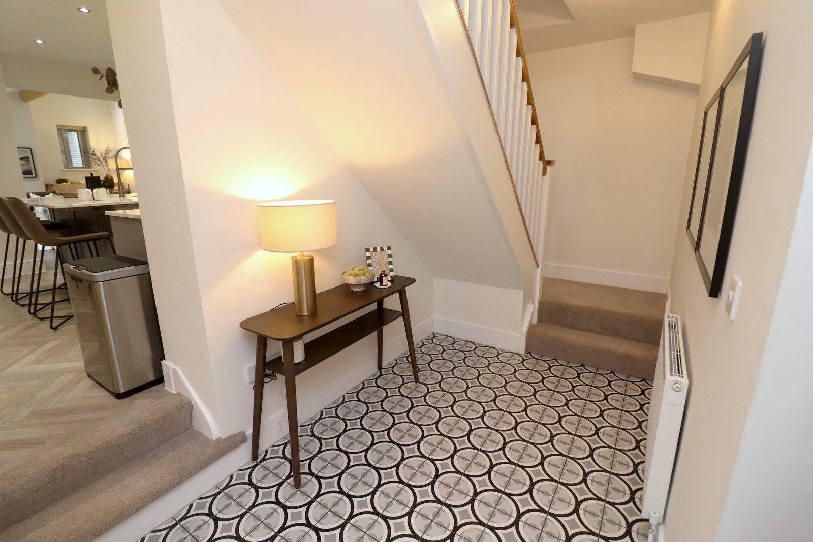 Hallway after: walnut console table with a lamp under the stairs, framed prints