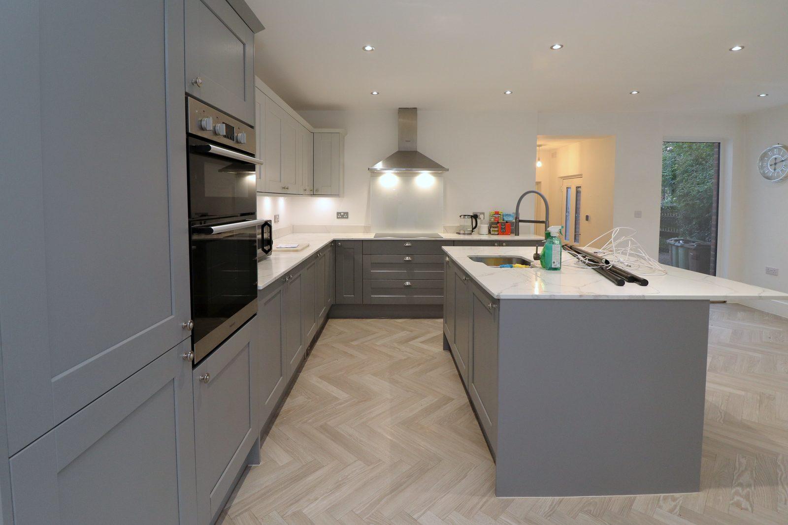 Kitchen before: run of grey units and island with nothing on the worktops