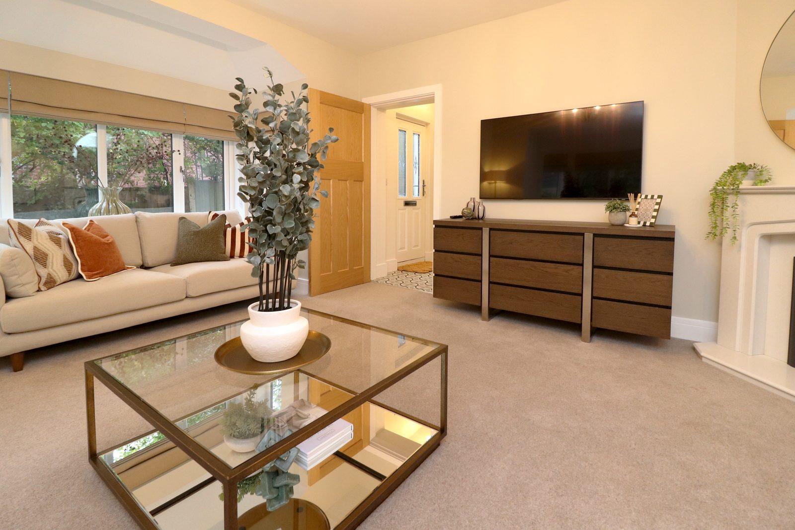 Living room after: sofa beneath the window, coffee table, television unit beside the fireplace