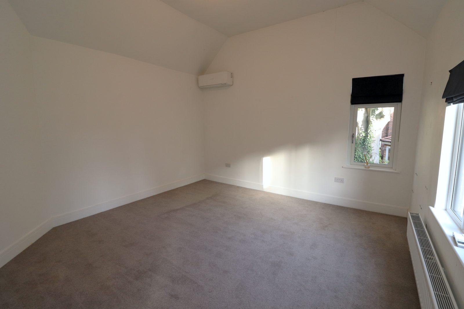 Main bedroom before: empty room with a vaulted ceiling and a window with a black blind