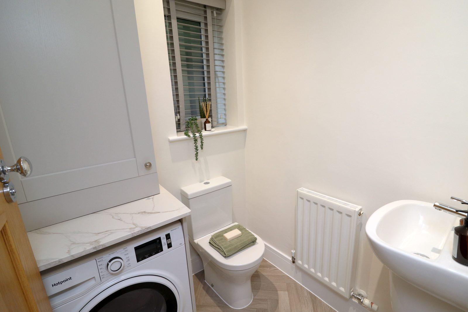 Utility room after: folded towel on the washing machine, plant on the windowsill